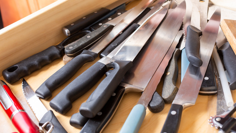 A cluttered drawer full of kitchen knives