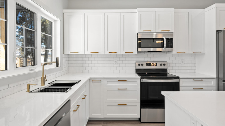 a modern kitchen with white cabinets and counter tops and brass fixtures