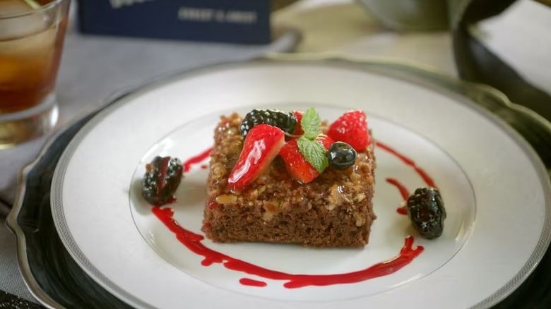Palmer House Brownie on a white plate with berries on top and a red swirl around it