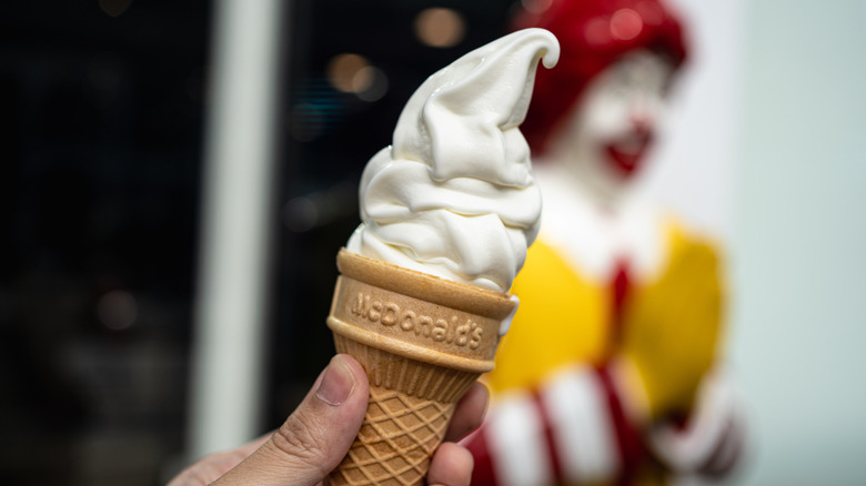 A hand holding a McDonald's ice cream cone